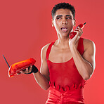 Phone call, beauty and gay man talking with a sassy attitude and red outfit in a studio. Conversation, mobile and beautiful lgbtq male with a cosmetics, makeup and style isolated by a red background.