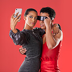 Selfie, fashion and funky people isolated on red background for queer, creative gen z and cyberpunk aesthetic. Futuristic glasses, profile picture and beauty couple of friends, model or youth makeup