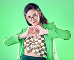 Portrait, hands and heart with a woman on a green background in studio for love, romance or health. Social media, emoji and affection with a trendy person posing or making a hand sign for style