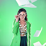 Education, smart and portrait of a woman with glasses isolated on a green background in a studio. Gen z, professor and teacher with paper, school work and tests flying for confidence on a backdrop