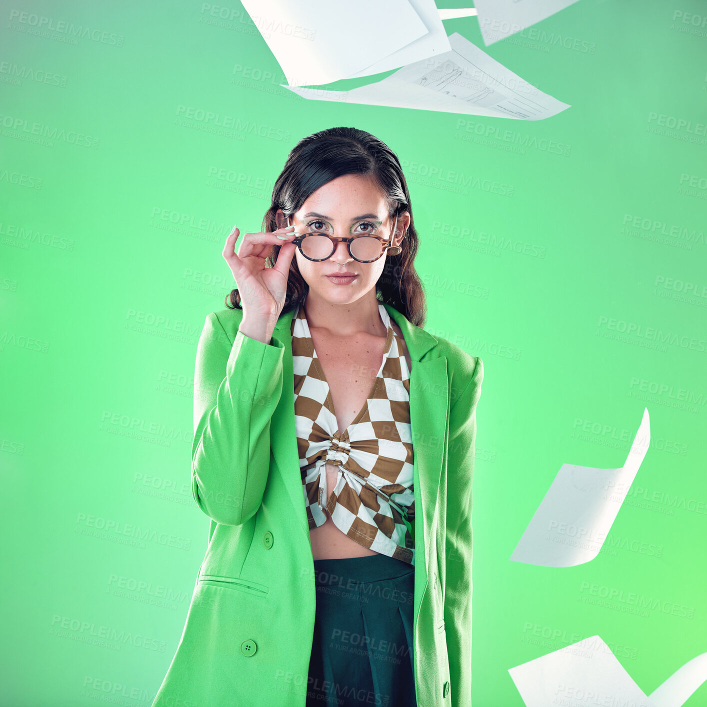 Buy stock photo Education, smart and portrait of a woman with glasses isolated on a green background in a studio. Gen z, professor and teacher with paper, school work and tests flying for confidence on a backdrop