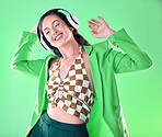 Music, fashion and woman dance on green background with trendy, stylish clothes and cosmetics in studio. Disco aesthetic, headphones and happy girl relax, dancing and streaming song, audio and radio