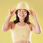 Fashion, asian and portrait of a woman with comic eyes isolated on a yellow background in studio. Happy, funny and face of a girl model with a hat and smile for advertising, cosmetics and motivation
