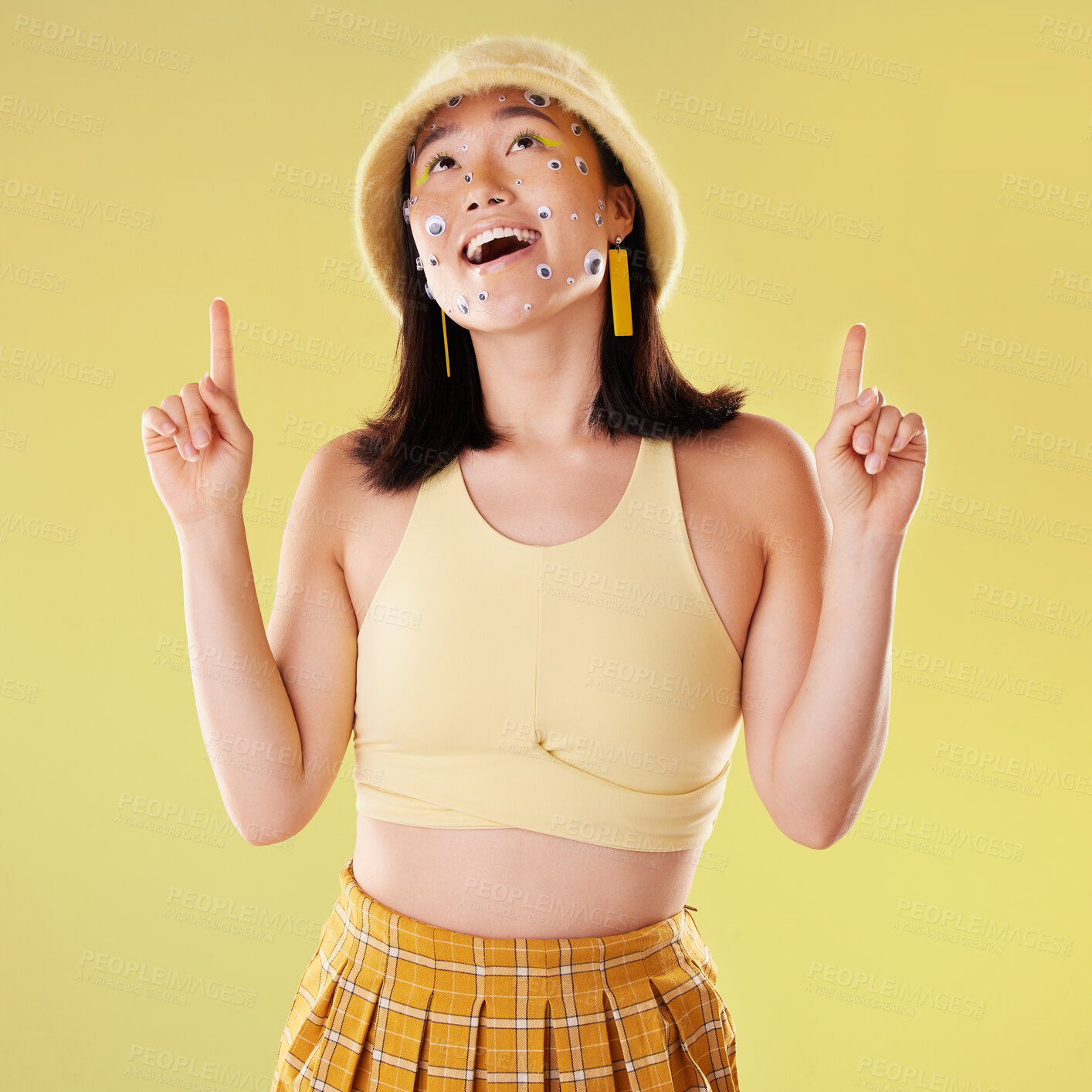 Buy stock photo Thinking, pointing and woman with eyes for comedy isolated on a yellow background in a studio. Idea, comic and Asian girl with a gesture up and facial product for expression and funny on a backdrop