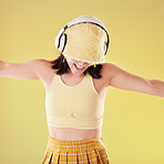 Music headphones, dance and woman in studio isolated on a yellow background. Eye stickers, freedom technology and happy female model dancing, singing and streaming radio, podcast and audio song.