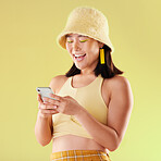 Phone, laughing and Asian woman typing in studio isolated on a yellow background. Comic emoji, technology and happy female model laugh at funny meme with mobile smartphone for social media or texting