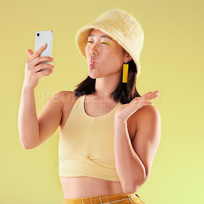 Selfie, beauty and Asian woman with funny face in studio isolated on a yellow background. Comic, crazy lips and funny female model taking pictures or photo for social media memory and profile picture