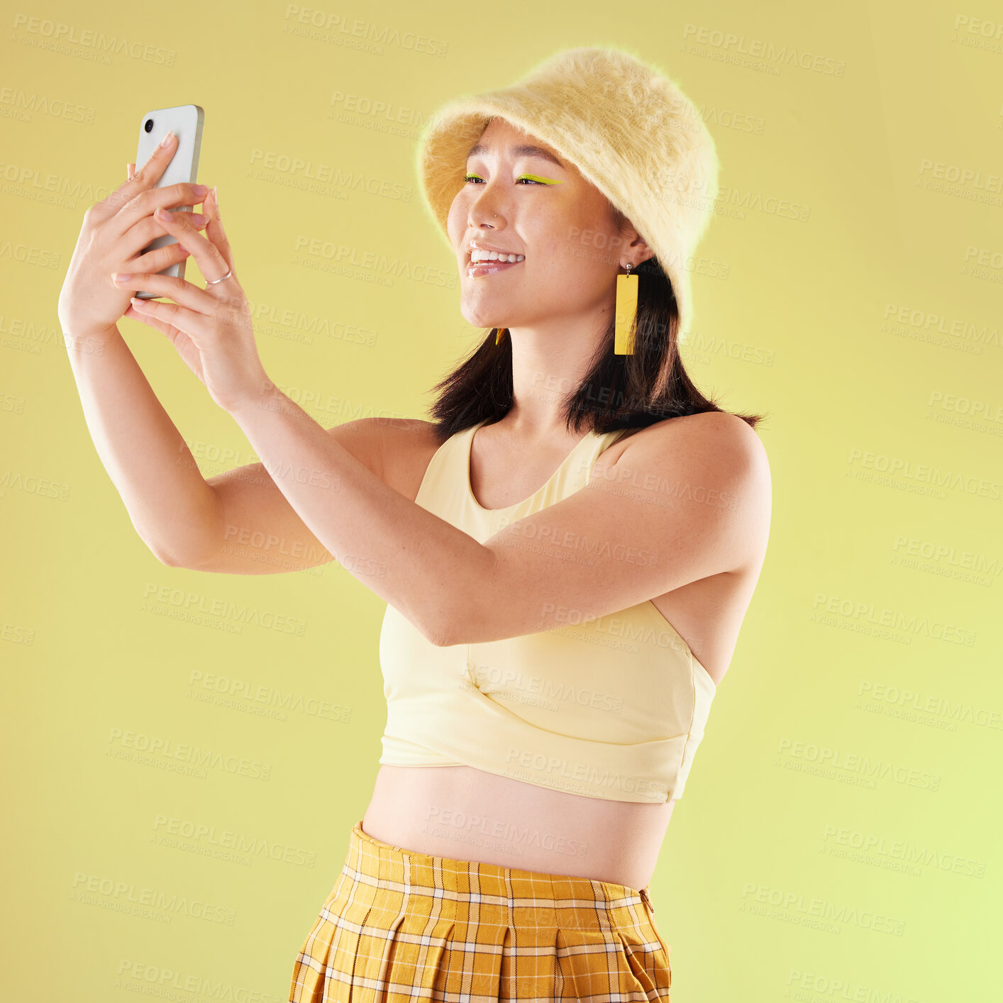 Buy stock photo Selfie, beauty and smile of Asian woman in studio isolated on a yellow background. Makeup, fashion hat or young female model taking pictures or photo for social media, profile picture or happy memory