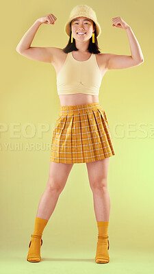 Buy stock photo Smile, empowerment and asian woman flexing arms, full body portrait of gen z model with trendy fashion win in studio. Feminism, power and strength, happy and strong girl isolated on yellow background