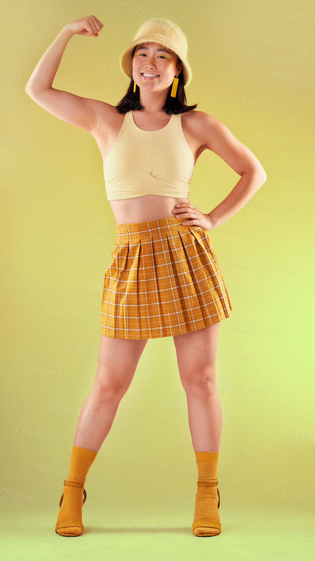 Buy stock photo Smile, power and asian woman flexing arm, full body portrait of gen z model with trendy fashion win in studio. Feminism, empowerment and strength, happy and strong girl isolated on yellow background.