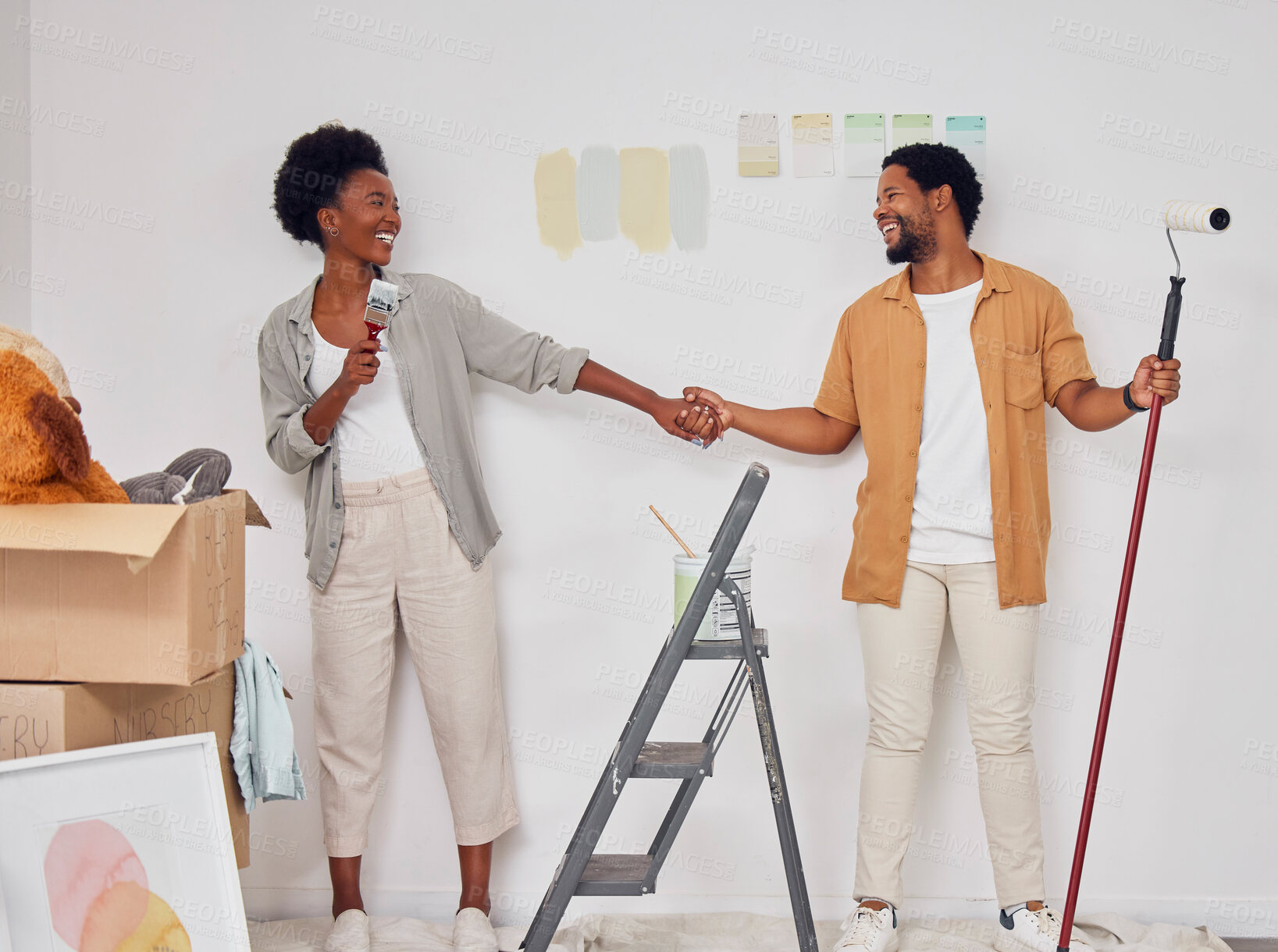 Buy stock photo Painting, holding hands or black couple singing in DIY, home renovation or remodel together with paintbrush. Playing, smile or fun African man laughing with happy woman dancing in house with teamwork