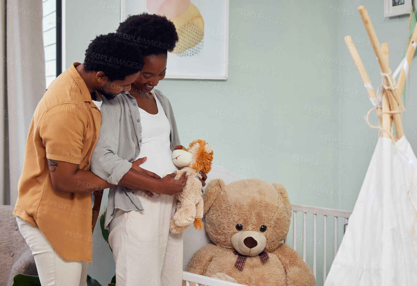 Buy stock photo Love, teddy bear and pregnant couple in the nursery with excitement while preparing for their baby. Happy, pregnancy and young African man with his maternal wife looking at toy together in bedroom.