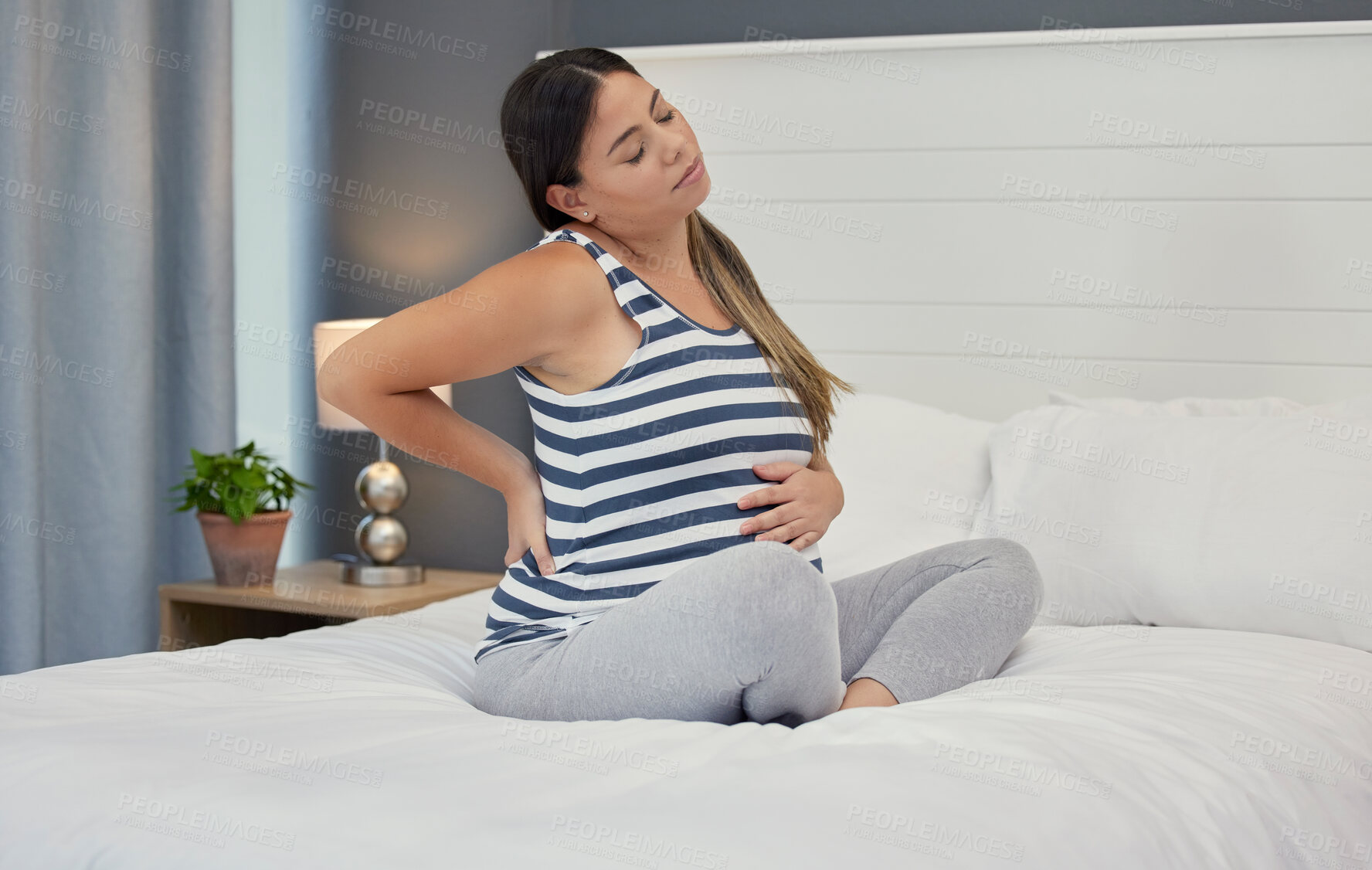 Buy stock photo Pregnant, bed and woman with back pain, maternity issues and anxiety with ache, muscle strain and cramps. Pregnancy, female or lady in bedroom, contractions and anxious with health problems or stress