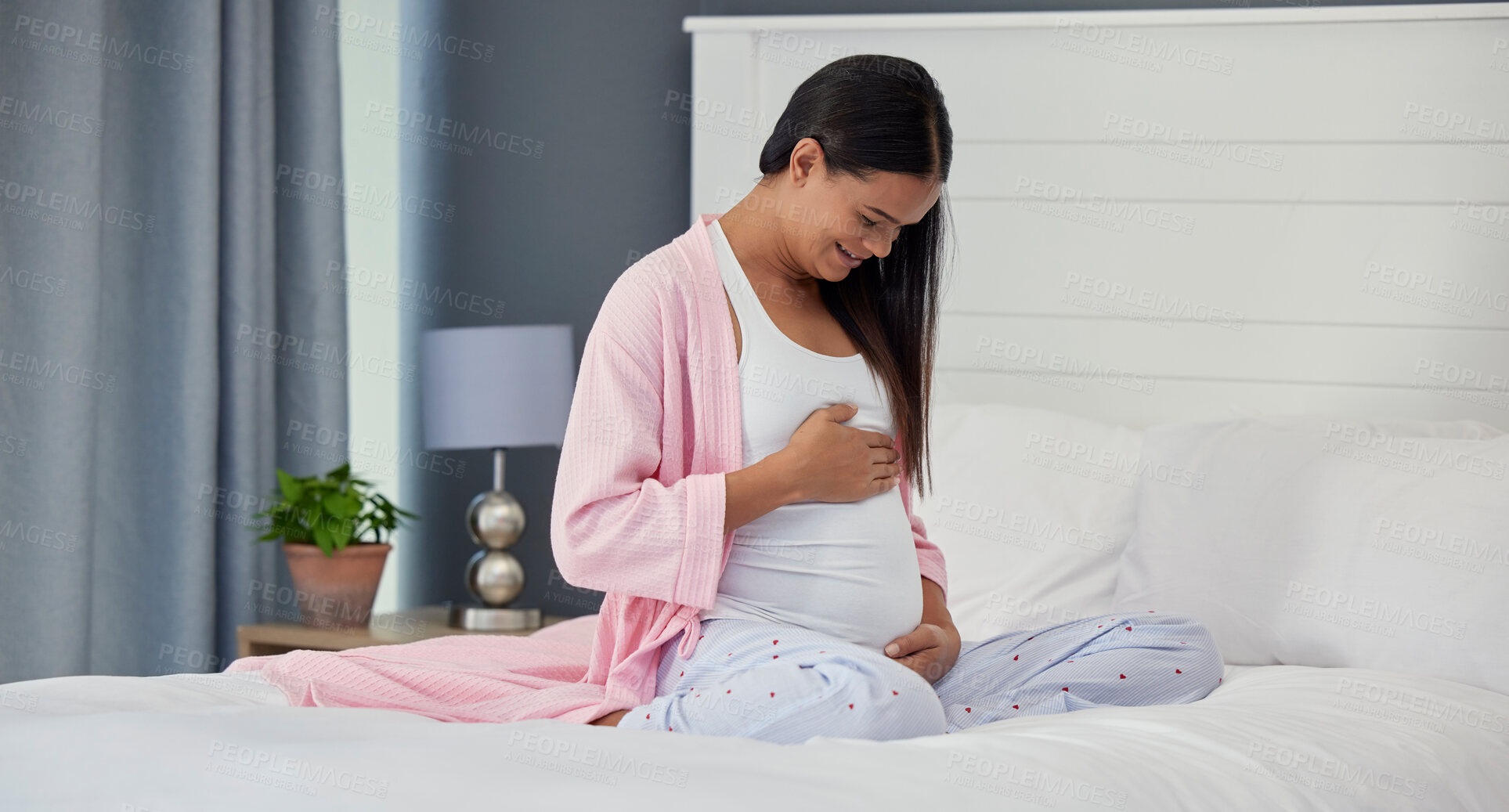 Buy stock photo Pregnant woman, stomach and love in home bedroom happy about bonding and movement. Mother to be person with hands on abdomen for healthy pregnancy development, body wellness and care on her bed