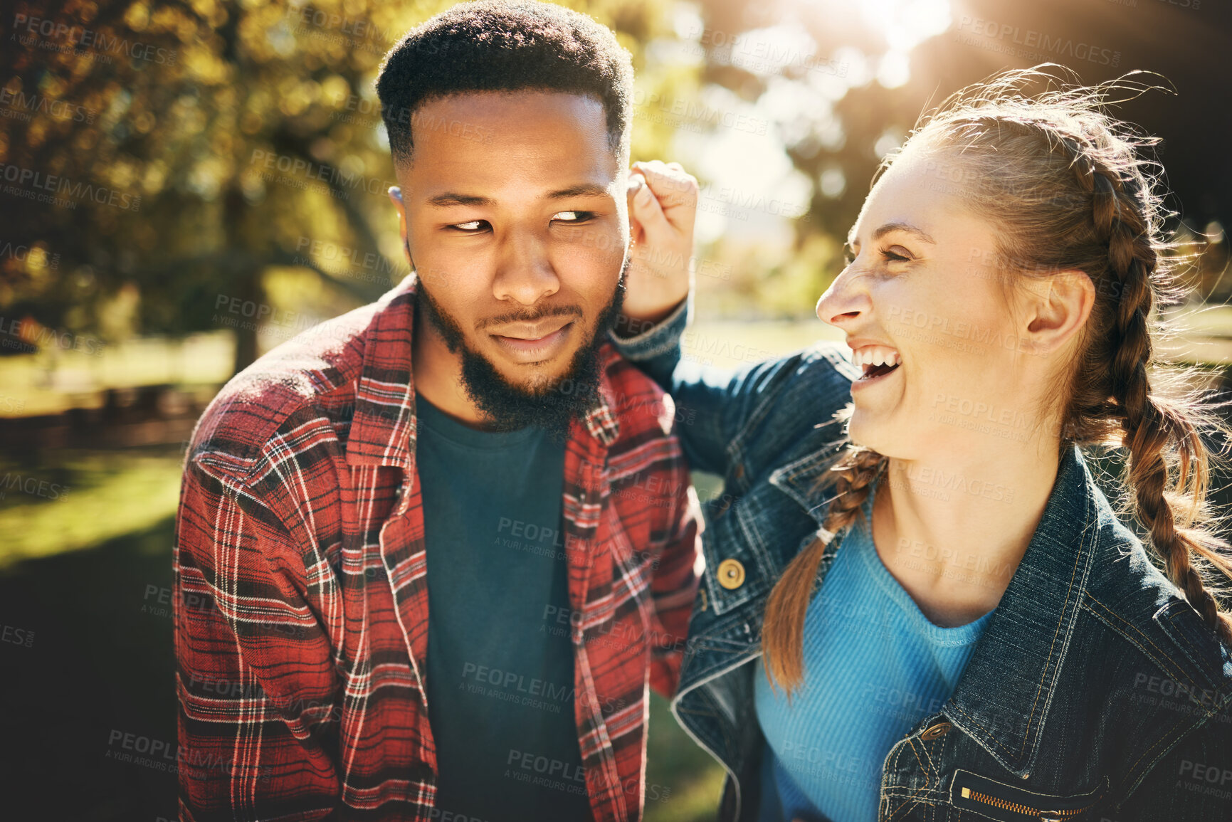 Buy stock photo Interracial couple, laughing and smile in nature for playful love, bonding and funny relationship. Happy woman holding man ear with laugh for fun loving care, affection or playing in a park outdoors