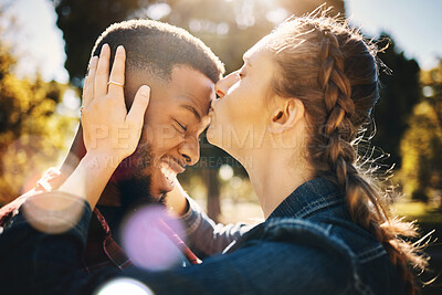 Buy stock photo Interracial couple, forehead kiss and smile in nature for love, bonding and embracing relationship. Happy woman kissing man on head smiling for loving care, affection or embrace in a park outdoors