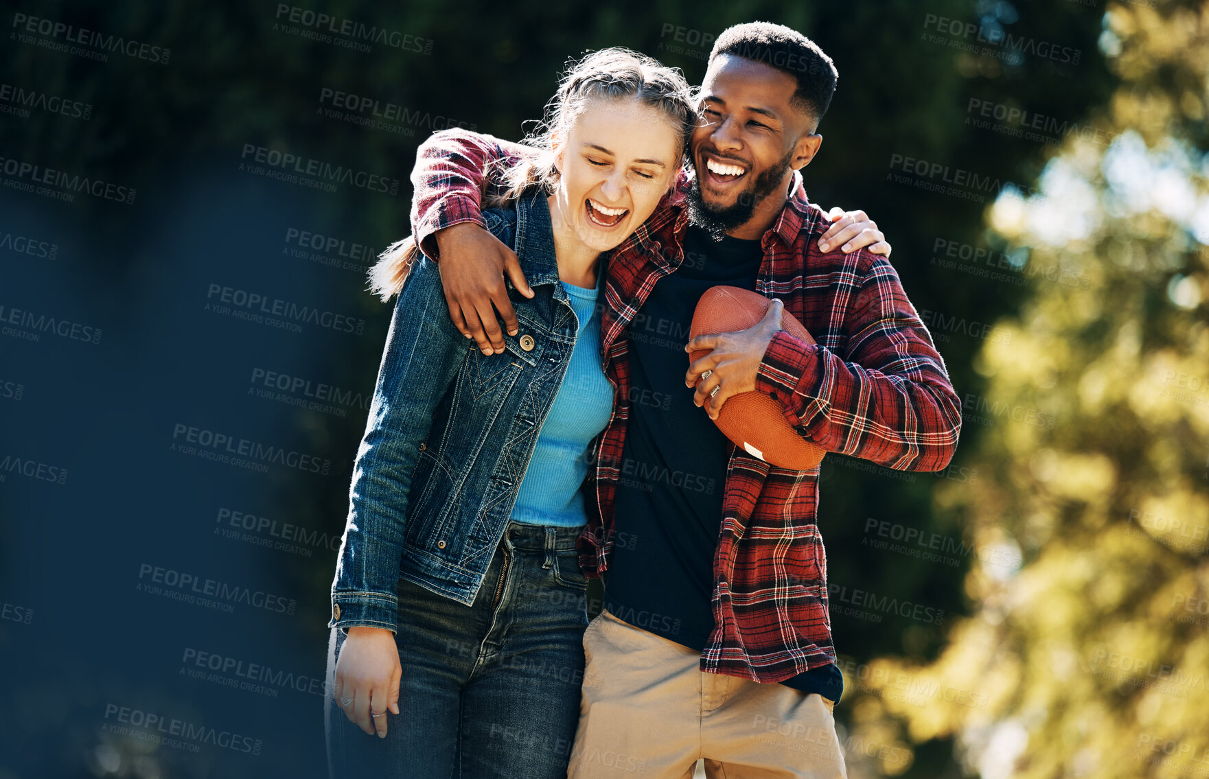 Buy stock photo Love, diversity couple and laughing in nature, having fun and playing football outdoors. Comic, interracial romance and happy black man and woman hug, laugh at funny joke and enjoying time together.