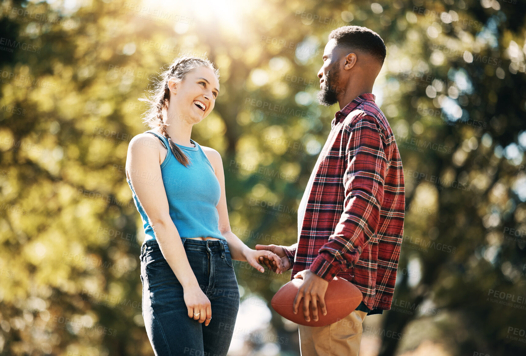Buy stock photo Couple, American football in park and happy together, summer with hand holding outdoor and sports in the sun. Commitment, trust and fitness, black man and woman, interracial relationship and care