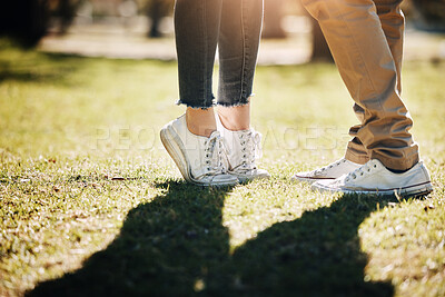 Buy stock photo Shoes, grass and love with a couple outdoor together, kissing for romance, dating or affection in summer. Nature, field or feet with a man and woman on a romantic date for relationship bonding
