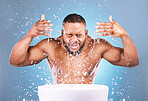Water splash, hands or black man cleaning face for beauty, skincare or fresh hygiene on blue background. African male model with wellness washing, grooming or cleansing for facial treatment in studio