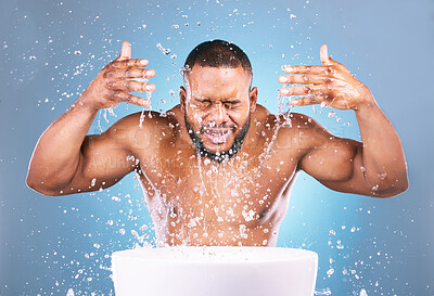 Buy stock photo Water splash, hands or black man cleaning face for beauty, skincare or fresh hygiene on blue background. African male model with wellness washing, grooming or cleansing for facial treatment in studio