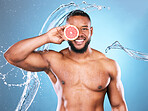 Portrait, water splash or black man with grapefruit for skincare, facial cleaning, vitamin c or cosmetic benefits in studio. Happy, smile or young male beauty model cleaning glowing face for wellness