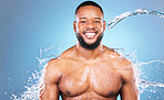 Bodybuilder, happy and water splash for man cleaning, hygiene and skincare isolated in studio blue background. Portrait, aqua and model washing smooth skin with glow, smile and self care