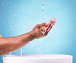 Closeup, hands and water splash for cleaning, basin and dermatology against blue studio background. Zoom, man and washing with bowl, wellness and morning routine or grooming, skincare and backdrop
