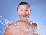 Portrait, man and water splash for cleaning, dermatology and guy against blue studio background. Face, happy male and gentleman with aqua, liquid and morning routine for washing, skincare or backdrop