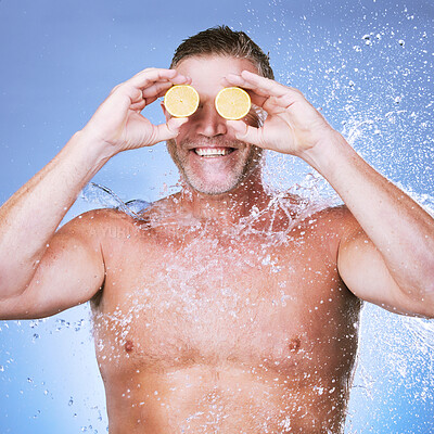 Buy stock photo Lemon in hands, water splash and man with face, beauty and skincare, eco friendly and organic on blue background. Hydration, vitamin c and hygiene with senior male, smile and citrus fruit with skin