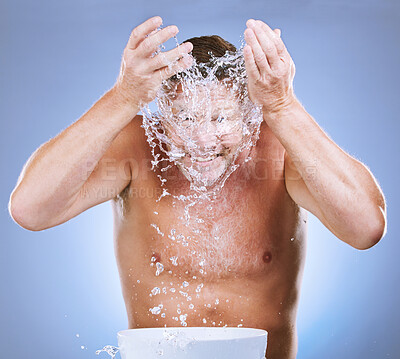 Buy stock photo Man, water splash and face wash by basin for hygiene or natural sustainability against a blue studio background. Male washing by sink for clean wellness, skincare or self care for facial treatment