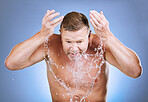 Man, water splash and cleaning face for skincare, wellness shower or blue background. Mature model, male beauty and clean facial for aesthetic, healthy glow and morning dermatology on studio backdrop