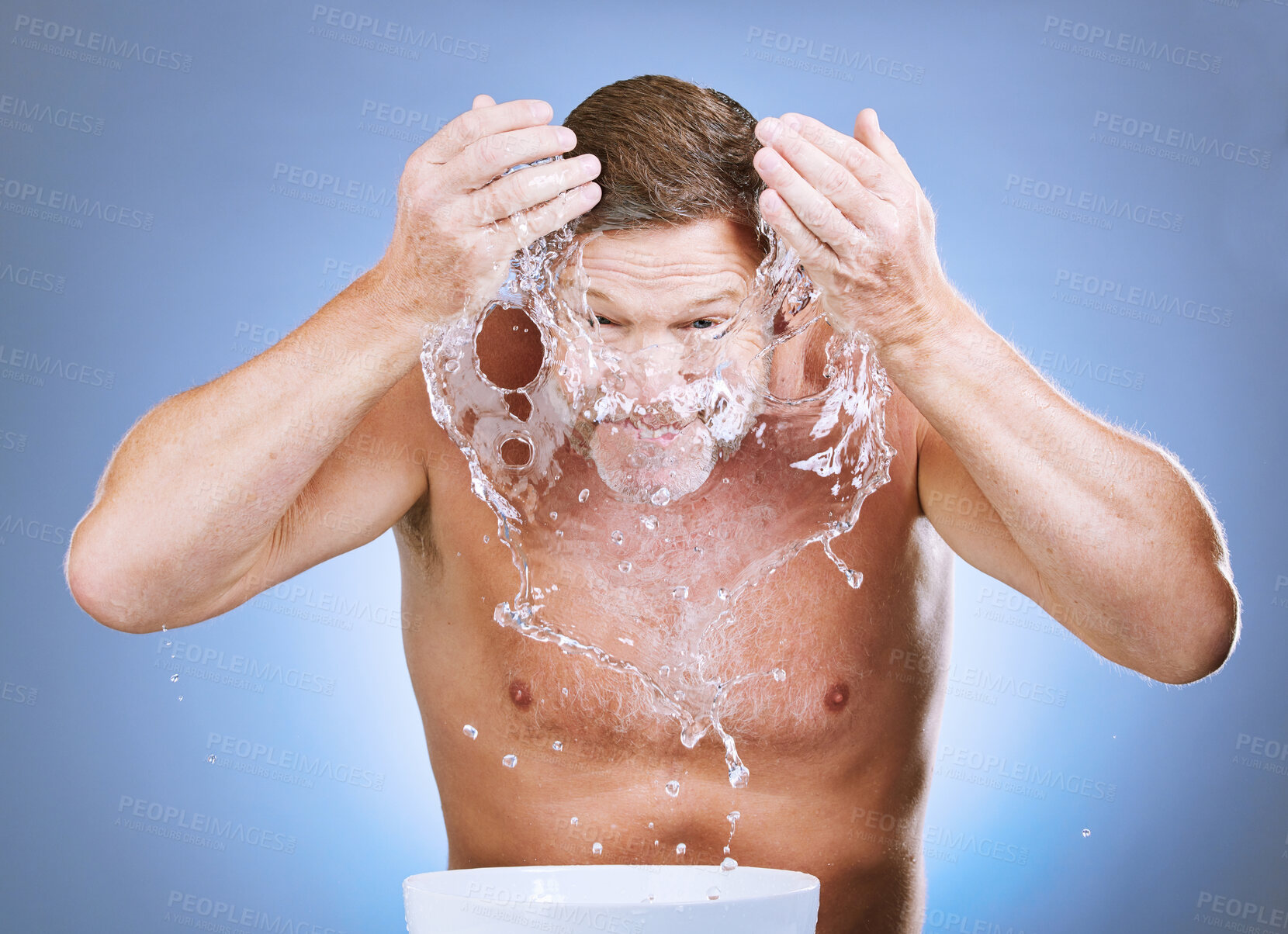 Buy stock photo Man, water splash and skincare hygiene by basin for face wash or natural sustainability against blue studio background. Male washing in facial treatment by sink for clean wellness or self care