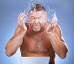 Man cleaning face, hands and water with hygiene and grooming with clean facial on blue background. Senior male washing skin, basin and beauty with natural cosmetic care, splash and dermatology