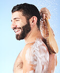 Shower, cleaning and man with brush, water splash and soap in studio for wellness, hygiene and grooming. Skincare, self care and male with foam, bath cosmetics and washing body on blue background