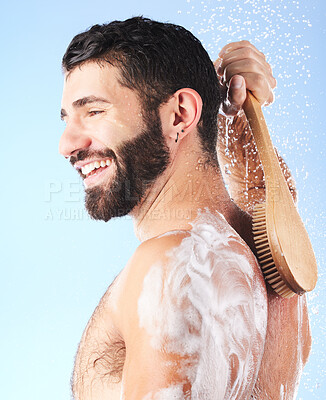Buy stock photo Shower, cleaning and man with brush, water splash and soap in studio for wellness, hygiene and grooming. Skincare, self care and male with foam, bath cosmetics and washing body on blue background