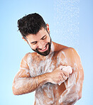Soap, shower and man with water splash, smile and hygiene in studio for wellness, cleaning and grooming. Skincare, healthy skin and happy male with foam, cosmetics and washing body on blue background