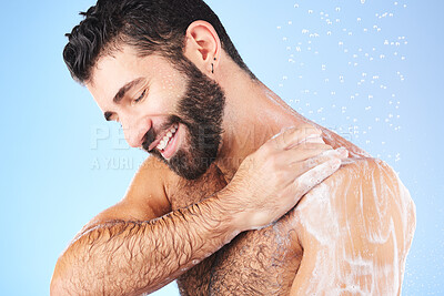 Buy stock photo Shower, cleaning and man with soap, smile and water splash in studio for wellness, hygiene and grooming. Skincare, healthy skin and male with foam, cosmetics and washing body on blue background 