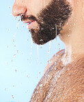 Man face, shower and profile of a model in water for cleaning, skincare and hygiene wellness. Isolated, blue background and studio with young person in bathroom for dermatology and self care routine
