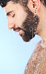 Water, shower and profile of a man in bathroom for cleaning, skincare and hygiene wellness. Isolated, blue background and studio with a male model with dermatology facial and self care routine