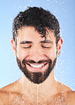 Man, shower water and smile of a model for beauty cleaning, skincare and hygiene wellness. Isolated, blue background and studio with a young person in bathroom for dermatology and self care routine