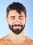 Man, water drop and face for hygiene, self care and cleaning on blue background in studio. Aesthetic model person for skincare, health and wellness with shower splash for facial dermatology cosmetics