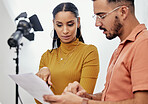 Documents, collaboration or planning with a photographer and model talking in a studio for creative production. Teamwork, designer or fashion with a designer man and woman at work on a magazine shoot