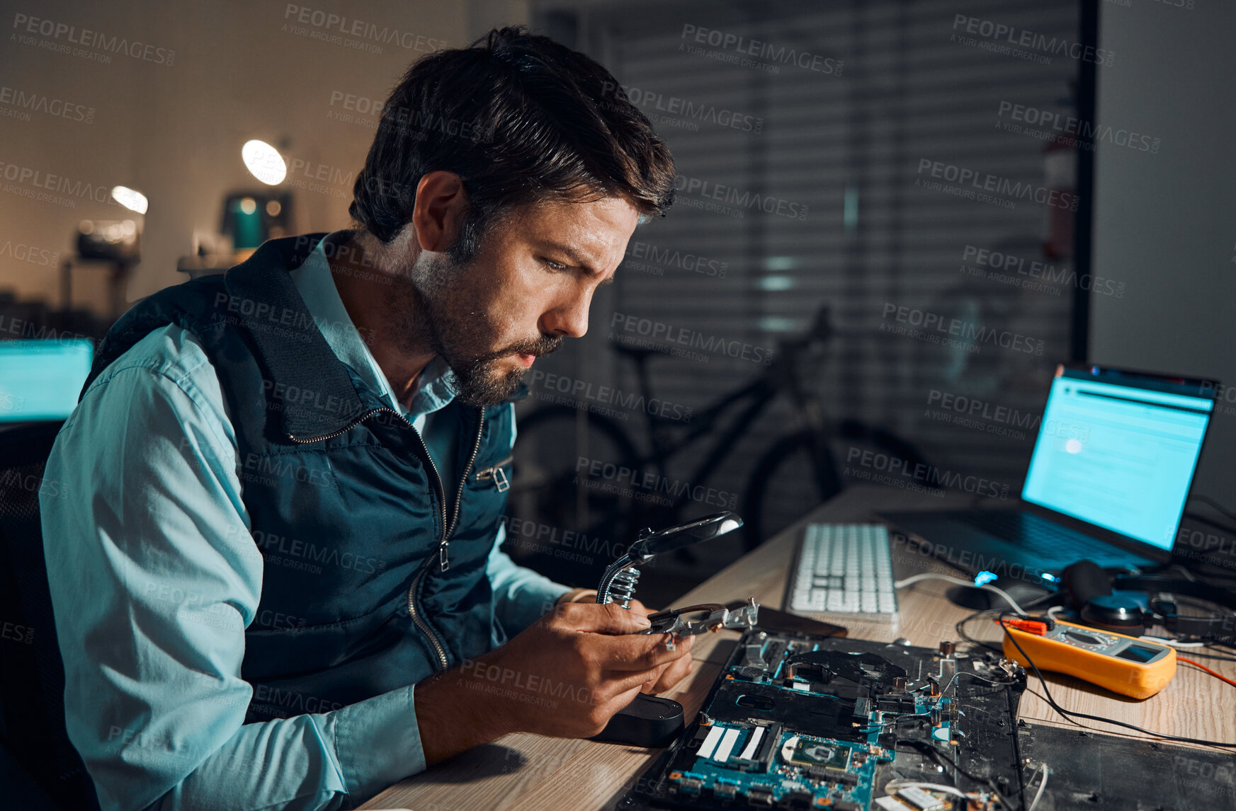 Buy stock photo Man, motherboard and magnifying glass at repair workshop in night for maintenance, computer tech or industry with focus. Technician, circuit and it job in dark with electronics, engineering and tools