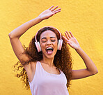 Music, freedom and dance with a black woman listening to the radio outdoor on a yellow wall background. Headphones, energy and face with an attractive young female streaming audio sound for fun