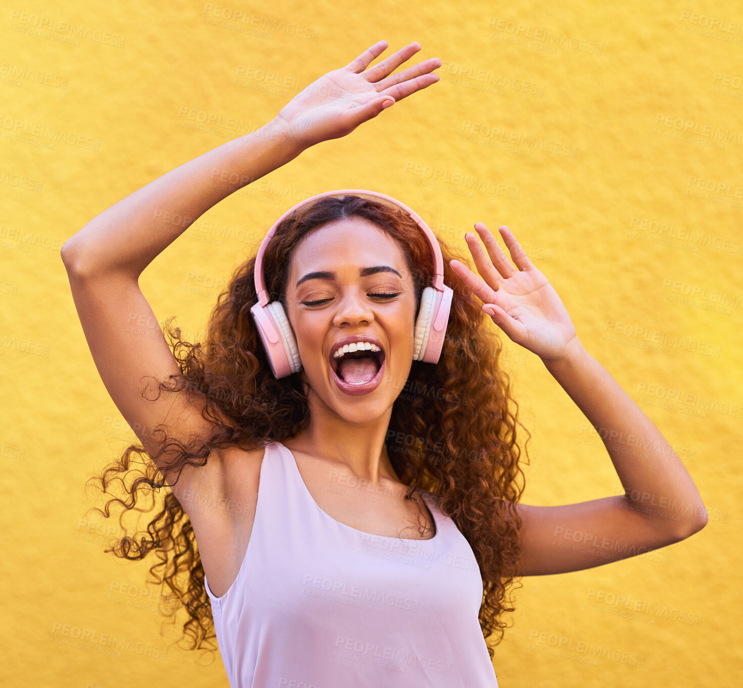 Buy stock photo Music, freedom and dance with a black woman listening to the radio outdoor on a yellow wall background. Headphones, energy and face with an attractive young female streaming audio sound for fun