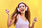 Music, idea and dance with a black woman listening to the radio outdoor on a yellow wall background. Headphones, energy and face with an attractive young female streaming audio sound for fun