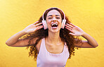 Music, portrait and laughter with a black woman listening to the radio outdoor on a yellow wall background. Headphones, energy and face with an attractive young female streaming audio sound for fun