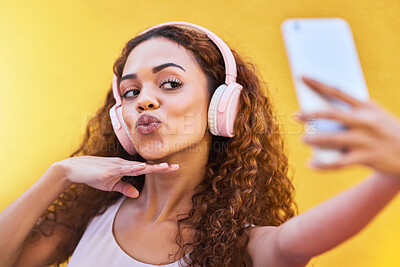 Buy stock photo Selfie, black woman and headphones for listening to music on yellow wall background. Face of happy gen z person pout lips with curly hair outdoor while streaming audio for influencer post in Colombia