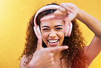 Music, frame and face with a black woman listening to the radio outdoor on a yellow wall background. Headphones, energy and face with an attractive young female streaming audio sound for fun